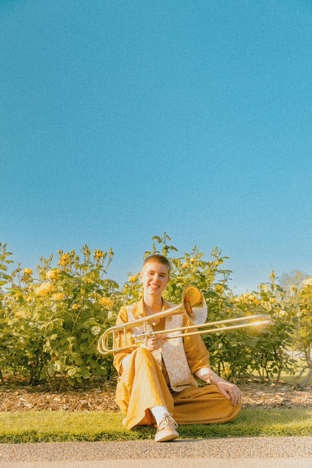 Jess sitting in a garden holding a trombone